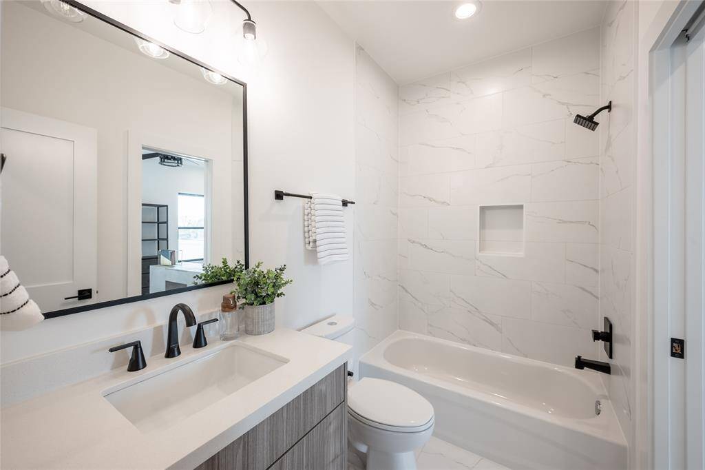 A blend of modern convenience and timeless design, this secondary bath features a sleek shower-tub combo and high-end finishes.