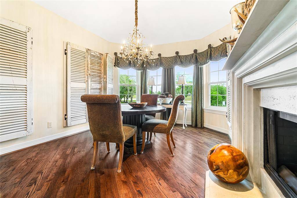 THE BREAKFAST AREA IS FLOODED WITH NATURAL LIGHT THANKS TO A WALL OF BAY WINDOWS OVERLOOKING LUSH GREENERY.