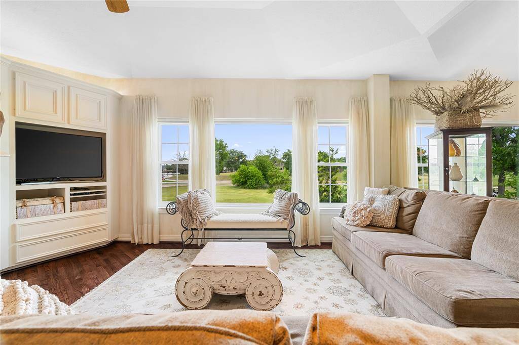 THE FAMILY ROOM IS FILLED WITH NATURAL LIGHT FROM A WALL OF WINDOWS THAT SHOWCASE SERENE GREEN VIEWS.