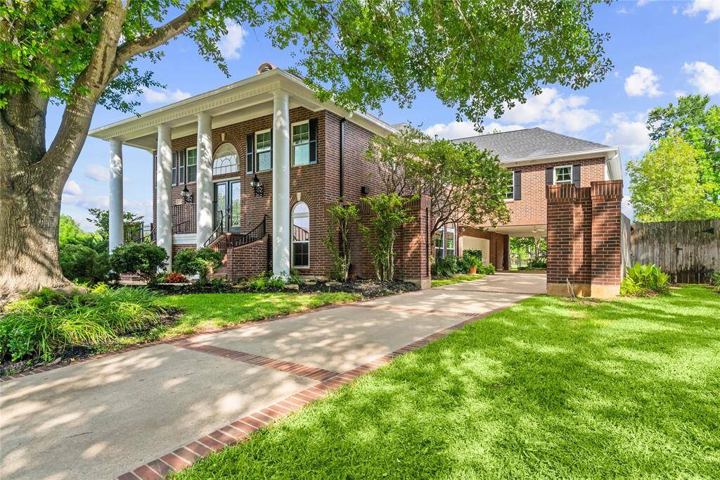 A GATED DRIVEWAY LEADS TO A COVERED BREEZEWAY AND ADDITIONAL PARKING, FLANKED BY A BRICK ENTRY GATE THAT COMPLEMENTS THE HOME'S ARCHITECTURAL STYLE.