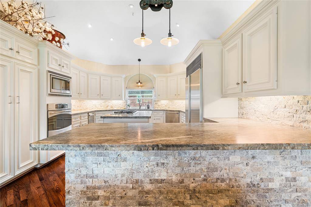 LUXURIOUS KITCHEN FEATURES  RICH STONE COUNTERTOPS, A TEXTURED STONE ISLAND FACE, AND UNDER-CABINET LIGHTING.