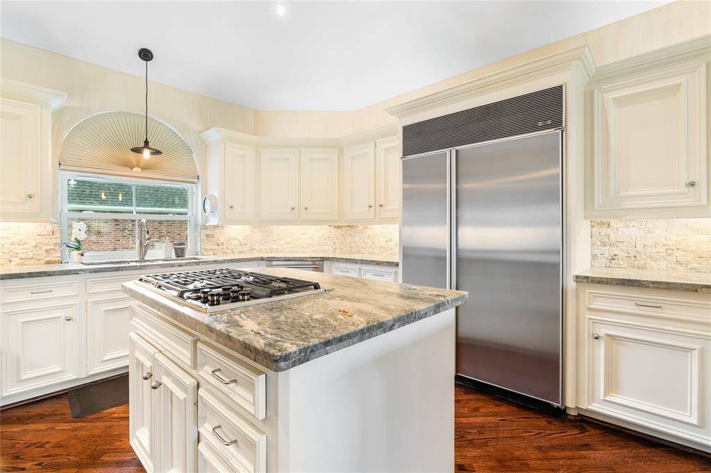 CENTERED AROUND A LARGE ISLAND WITH A BUILT-IN GAS COOKTOP, LUXURIOUS NATURAL STONE COUNTERS, AND TONS OF STORAGE SPACE—MAKING IT A DREAM FOR HOME CHEFS.