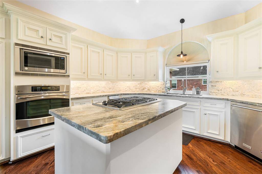 STAINLESS STEEL APPLIANCES, EDISON BULB PENDANT LIGHTS AND A LARGE ARCHED WINDOW ABOVE THE SINK ADD A TOUCH OF LUXURY AND NATURAL LIGHT TO THE SPACE.