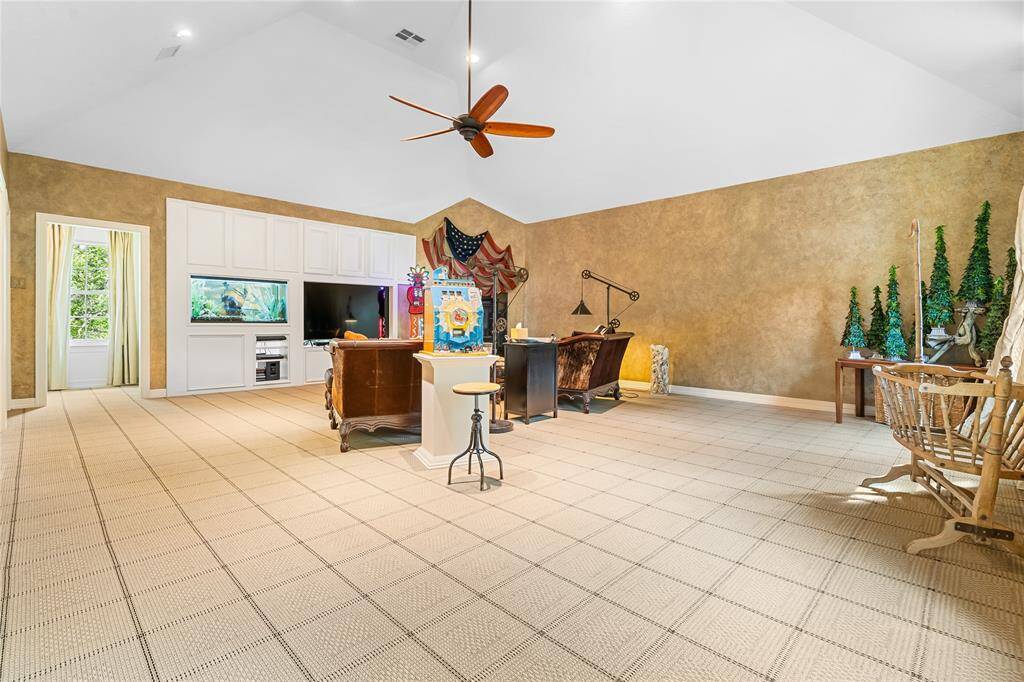 THIS EXPANSIVE GAME ROOM OFFERS INCREDIBLE FLEXIBILITY WITH BUILT-IN CABINETRY, A LARGE ENTERTAINMENT CENTER, AND ROOM FOR LOUNGING OR PLAY.