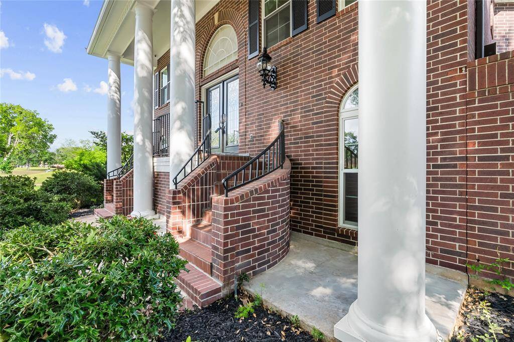 GRAND ENTRANCE WITH ELEGANT BRICK STEPS, DOUBLE DOORS, AND MASSIVE COLUMNS THAT ADD A TOUCH OF SOUTHERN CHARM.