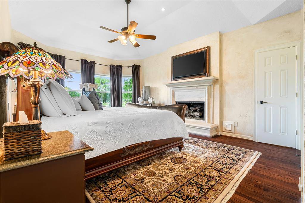 THE PRIMARY BEDROOM, LOCATED ON THE SECOND FLOOR, FEATURES A COZY FIREPLACE AND RICH HARDWOOD FLOORS.