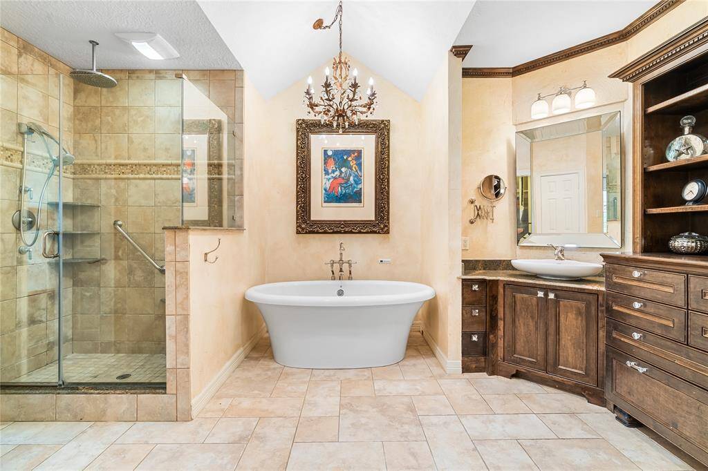 LUXURIOUS PRIMARY BATHROOM SHOWCASING A FREESTANDING SOAKING TUB, A WALK-IN SHOWER WITH RAINFALL HEAD, AND A STUNNING VAULTED CEILING WITH CHANDELIER.