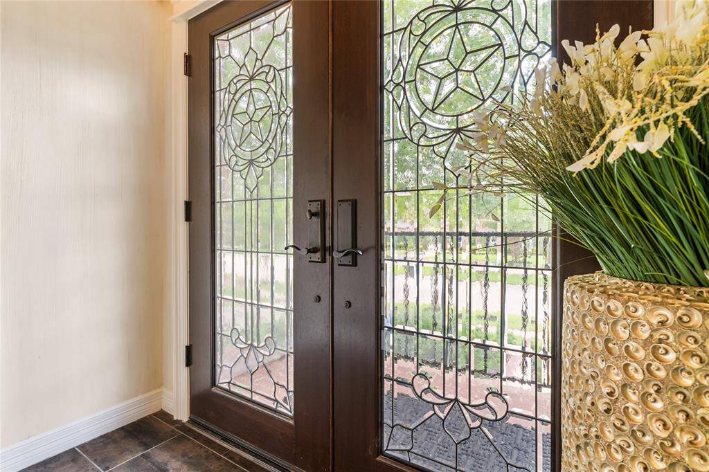 WELCOME GUESTS THROUGH A STRIKING DOUBLE DOOR ENTRYWAY FEATURING ORNATE LEADED GLASS PANELS.