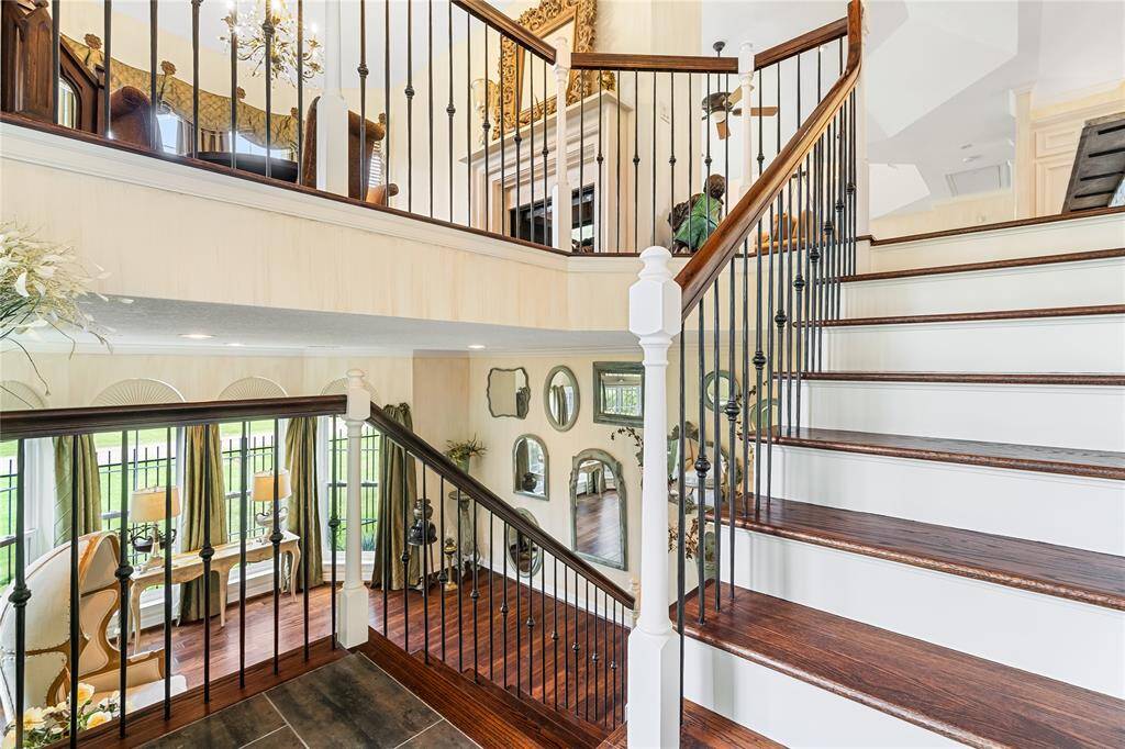THE DRAMATIC STAIRCASE OFFERS A GRAND VIEW OF THE OPEN LAYOUT, SHOWCASING ELEGANT WROUGHT IRON BALUSTERS.