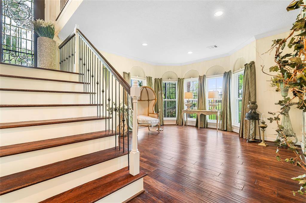 ELEGANT ENTRYWAY WITH WARM HARDWOOD FLOORS AND A STUNNING WROUGHT IRON STAIRCASE.