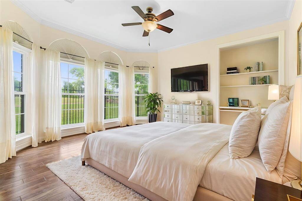 ANOTHER FIRST FLOOR BEDROOM SHOWCASING A WALL OF ELEGANT ARCH-TOP WINDOWS THAT FILL THE ROOM WITH NATURAL LIGHT AND OFFER SERENE VIEWS OF THE GOLF COURSE. **This room has been virtually staged.