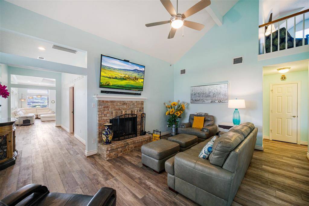 Cozy den with brick fireplace, high ceilings, and abundant natural light—perfect for relaxation.