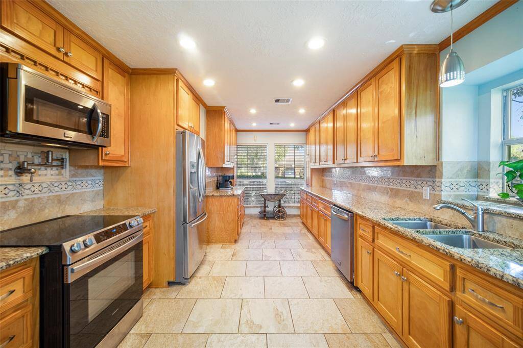 The kitchen boasts granite countertops, stainless steel appliances, and a pot filler above the cooktop.