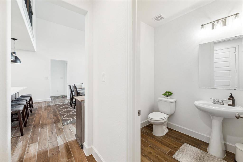 The half bathroom off the kitchen has a modern pedestal sink.