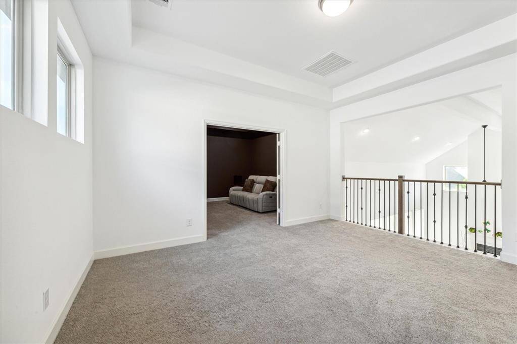 The upstairs game room features plush carpet and high ceilings.