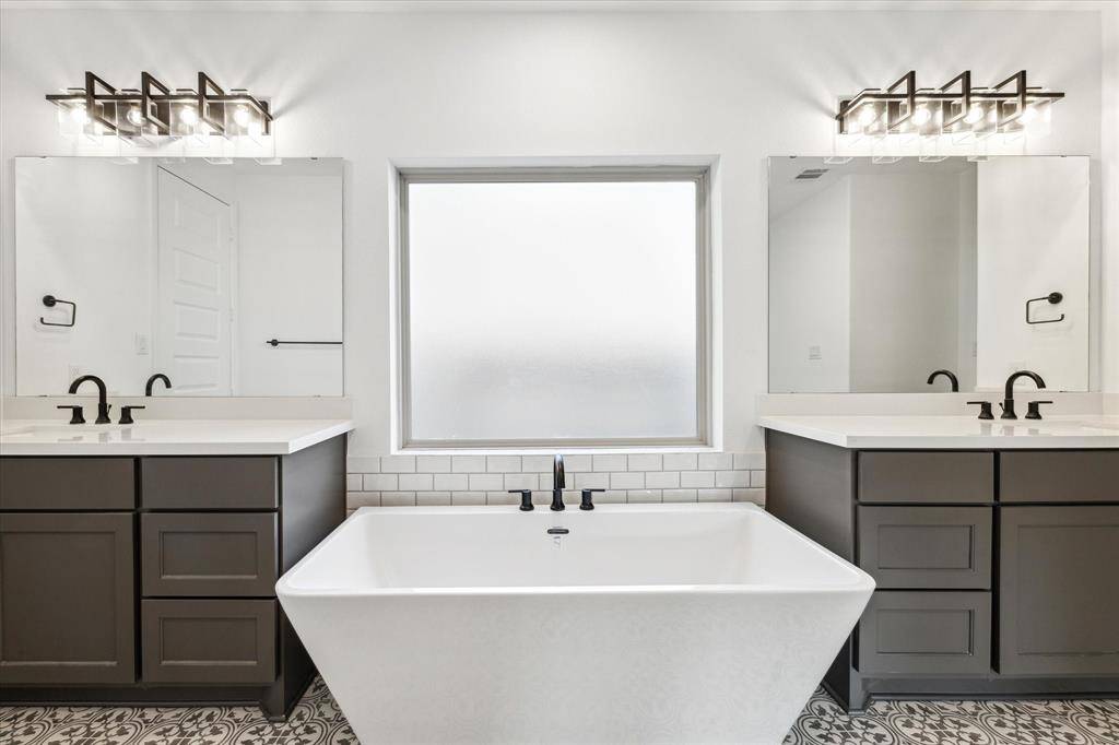 The primary bathroom features dual sinks, beautiful flooring, large frosted window, and a soaking tub.