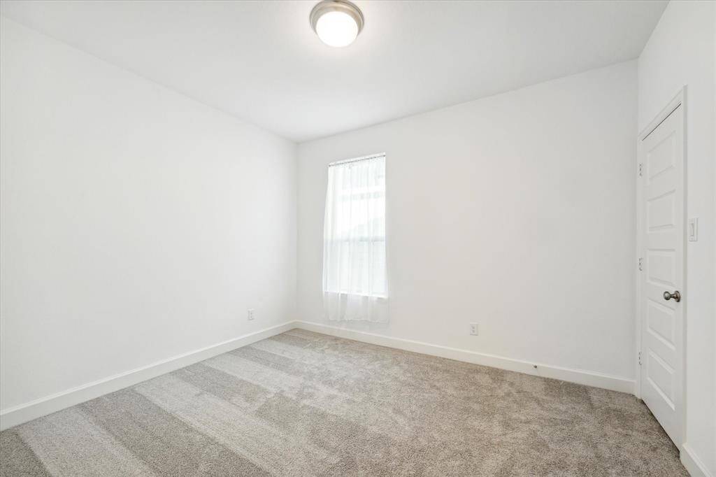 Fourth bedroom features awindow and plush carpet.