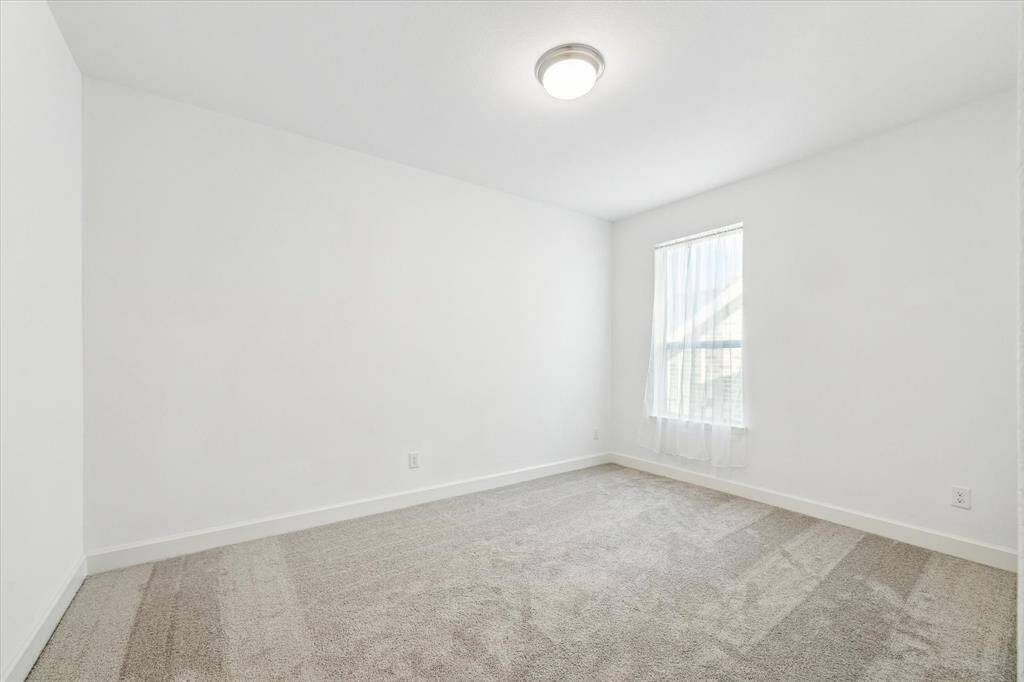 Fifth bedroom features awindow and plush carpet.