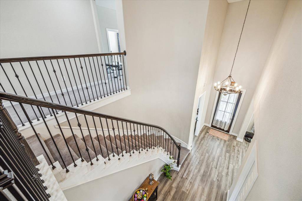 The overlook to the front foyer showcases a grand two-story entryway with a striking chandelier and an elegant wrought iron staircase. The open design allows for a seamless flow between levels, enhancing the home's spacious and airy feel.