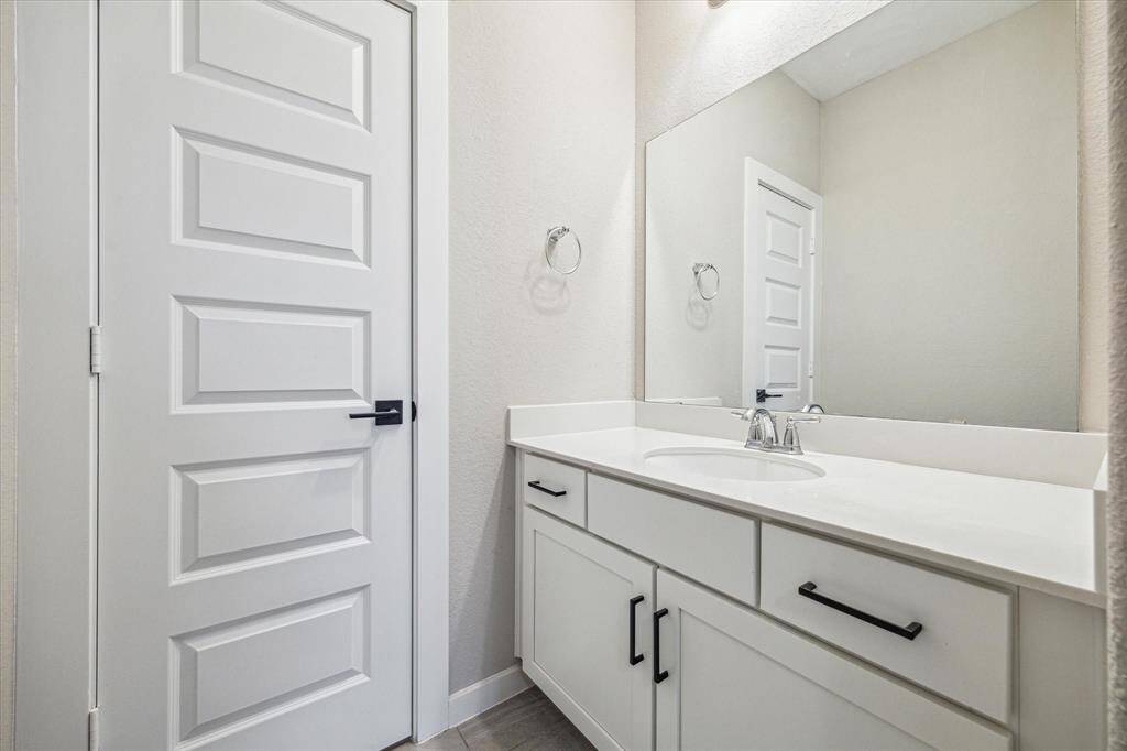 This is the second bathroom upstairs, designed in a Jack and Jill style for shared convenience. It features a white vanity with ample storage, a large mirror, and a bathtub with tiled walls and a shower curtain for privacy.