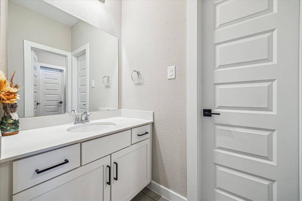 This is the second bathroom upstairs, designed in a Jack and Jill style for shared convenience. It features a white vanity with ample storage, a large mirror, and a bathtub with tiled walls and a shower curtain for privacy.