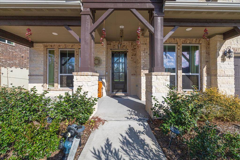 The inviting entryway of this home in Harper’s Preserve features a charming covered front porch with elegant stone and brick accents. Surrounded by lush landscaping, the pathway leads to a stunning front door that warmly welcomes you into this beautiful property.