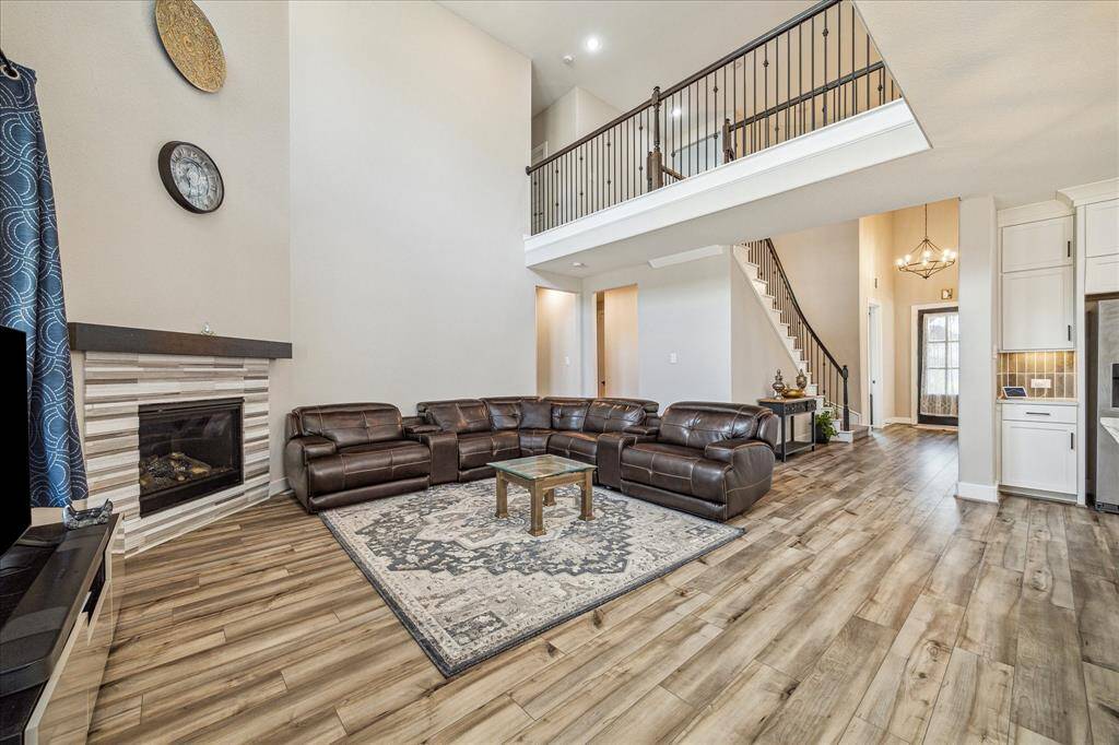 This elegant living area showcases an open-concept design with high ceilings and a modern fireplace. The space seamlessly flows into the kitchen and features a stylish staircase leading to the second floor, enhancing the home's spacious and inviting feel.