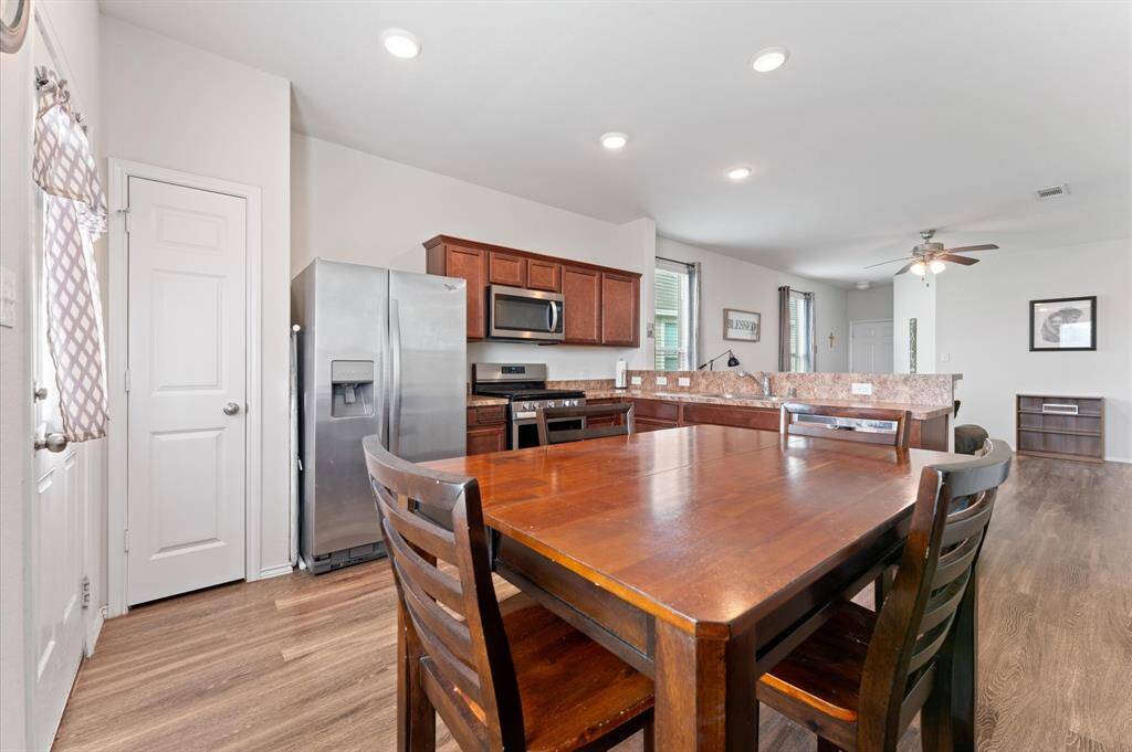 Open-concept kitchen and breakfast/dining area. The kitchen features stainless steel appliances, dark wood cabinets. Recessed lighting and a ceiling fan enhance the modern, airy feel.