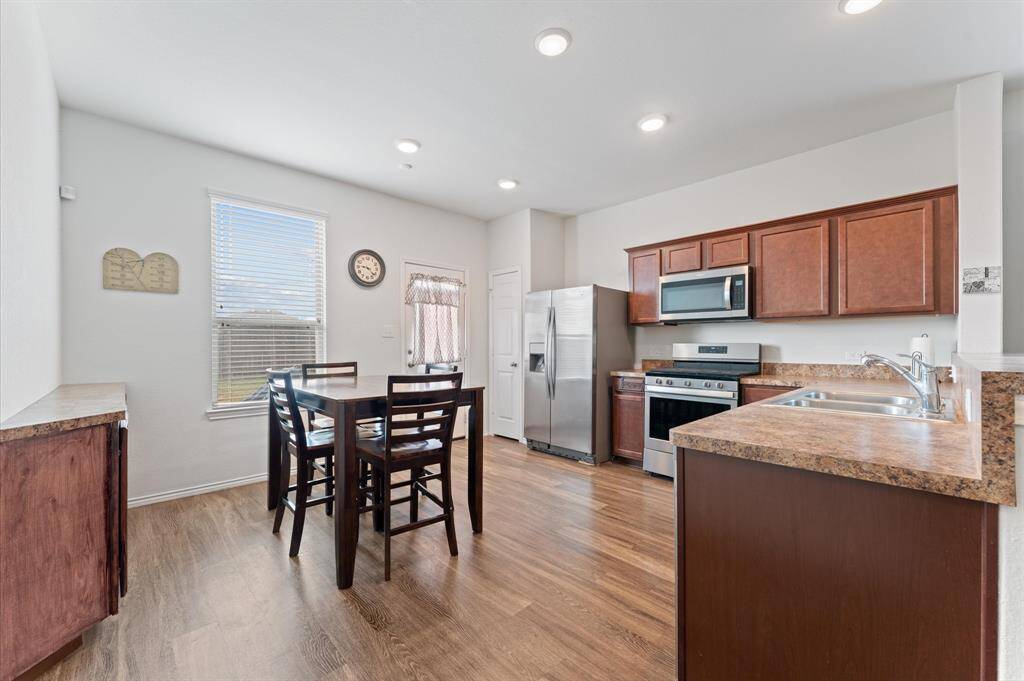 Open-concept kitchen and breakfast/dining area. The kitchen features stainless steel appliances, dark wood cabinets. Beautiful stained handmade buffet for entertainment.