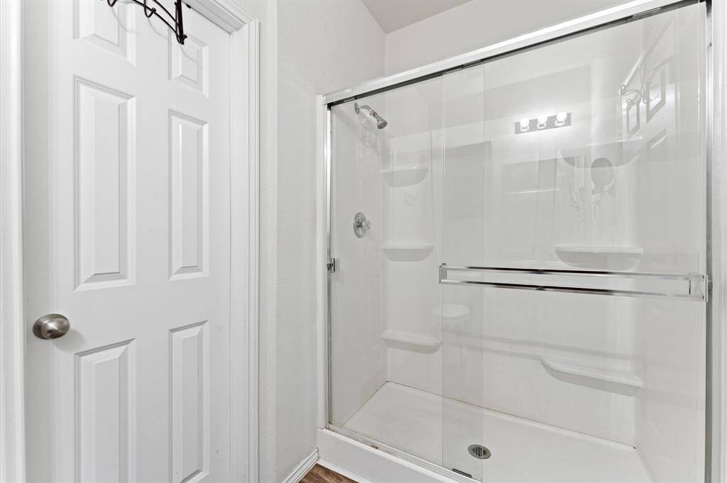Primary modern bathroom with a glass-enclosed shower and a white interior.