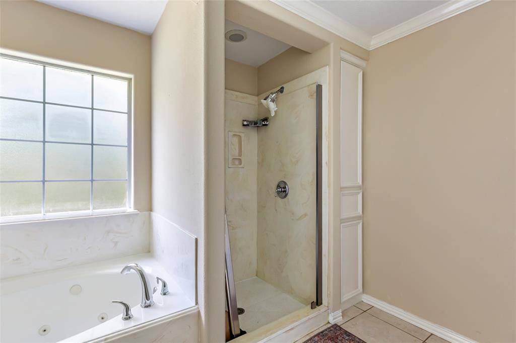 This spacious primary bathroom combines style and functionality, featuring ample storage throughout to keep everything organized.
