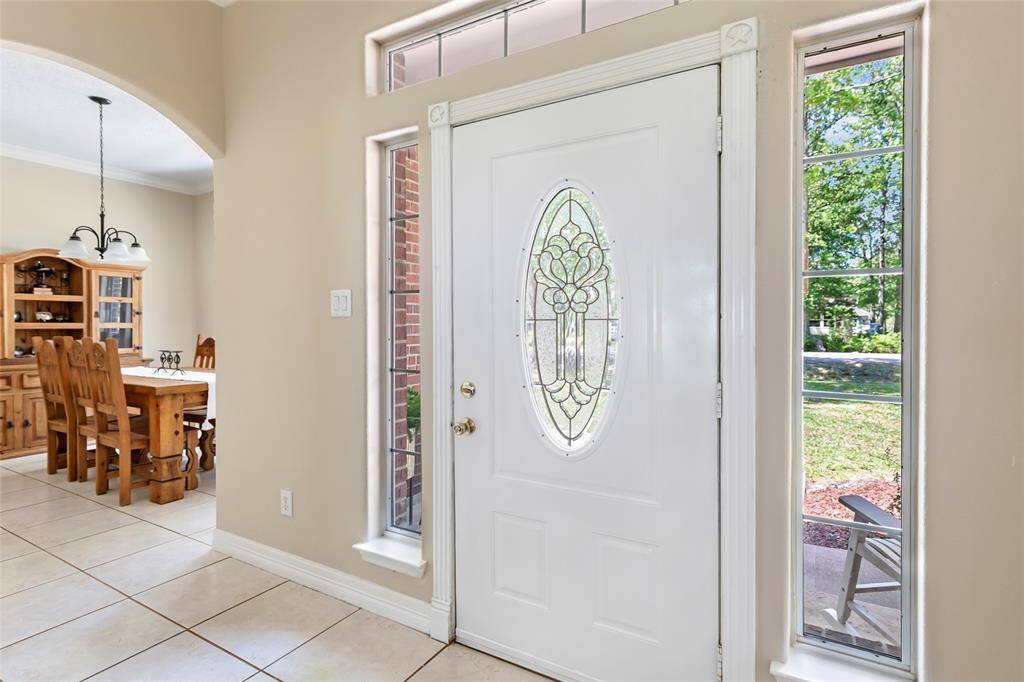 Make a grand first impression with this stunning decorative front door, framed by beautiful surrounding windows that fill the foyer with natural light.