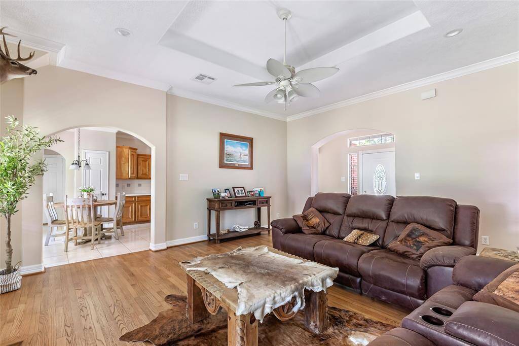 Spacious and inviting living room features elegant crown molding, trey ceilings, and large windows that flood the space with natural light.