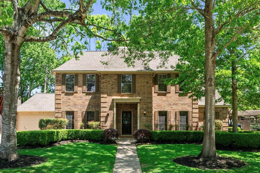 Charming two-story brick home with a welcoming front path, surrounded by mature trees and well-maintained landscaping. Features a spacious garage and offering great curb appeal in a serene setting.