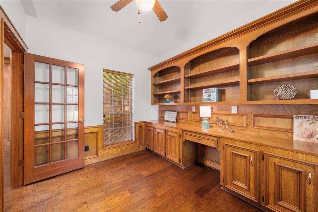 This private home office/study is just off the family room & features a spacious built-in wooden desk and shelving unit. It includes large windows for natural light and a glass-paneled door for added elegance & privacy.