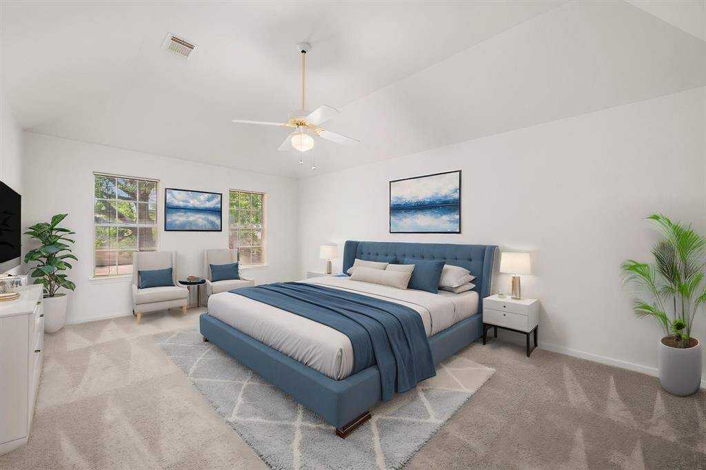 The bright and spacious Primary Bedroom features a vaulted ceiling and recent neutral carpet. The room is virtually furnished with an upholstered bed, matching decor, and modern artwork to complete the inviting atmosphere.