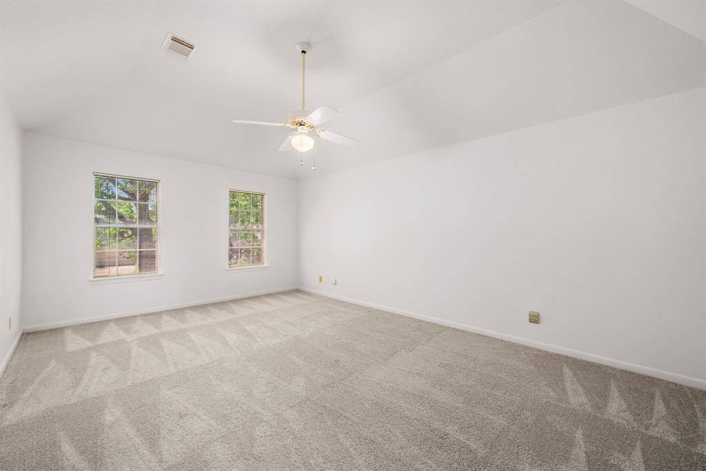 The bright Primary Bedroom features freshly painted white walls, a high ceiling with a fan, and two large windows that let in plenty of natural light. The neutral carpet adds warmth, making it versatile for any decor style.
