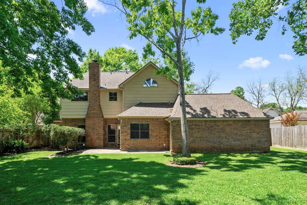 This photo shows the rear view of this charming two-story home with a brick and siding exterior. The home has a gabled roof and a prominent chimney.