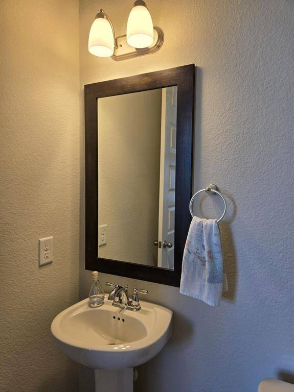 Cute and spacious powder room with pedestal sink, nice mirror and trendy light fixture.
