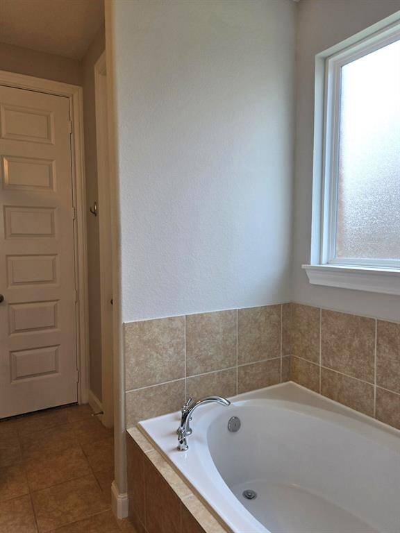 View of soaking tub in main suite and door to spacious walk in closet! Water closet is on right behind tub.