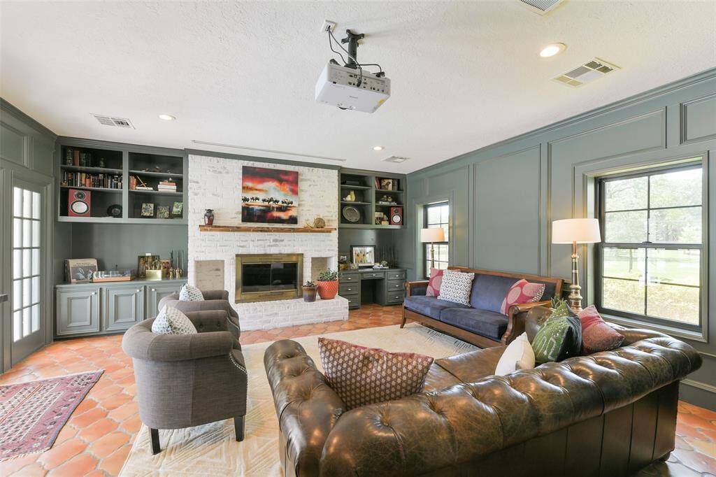 Large living room/media room with drop down projection screen in front of the floor to ceiling stone fireplace.  Note the solid wood mantle and built ins on either side of the fireplace.
