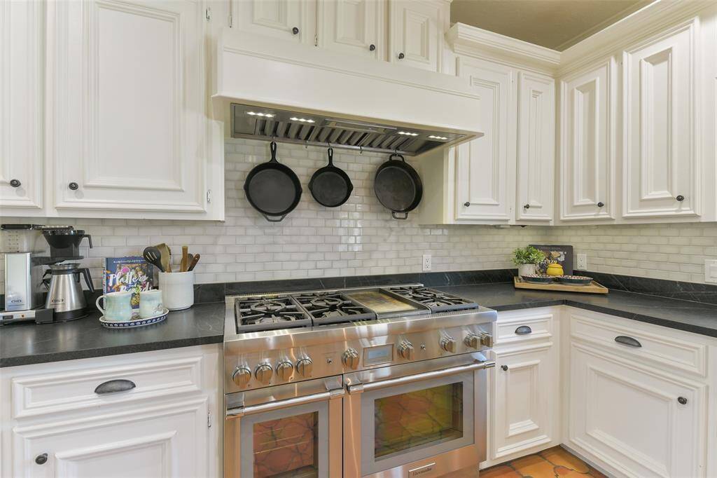 Chef's dream Thermador double oven, 6 burner gas stove with griddle and custom vent hood.