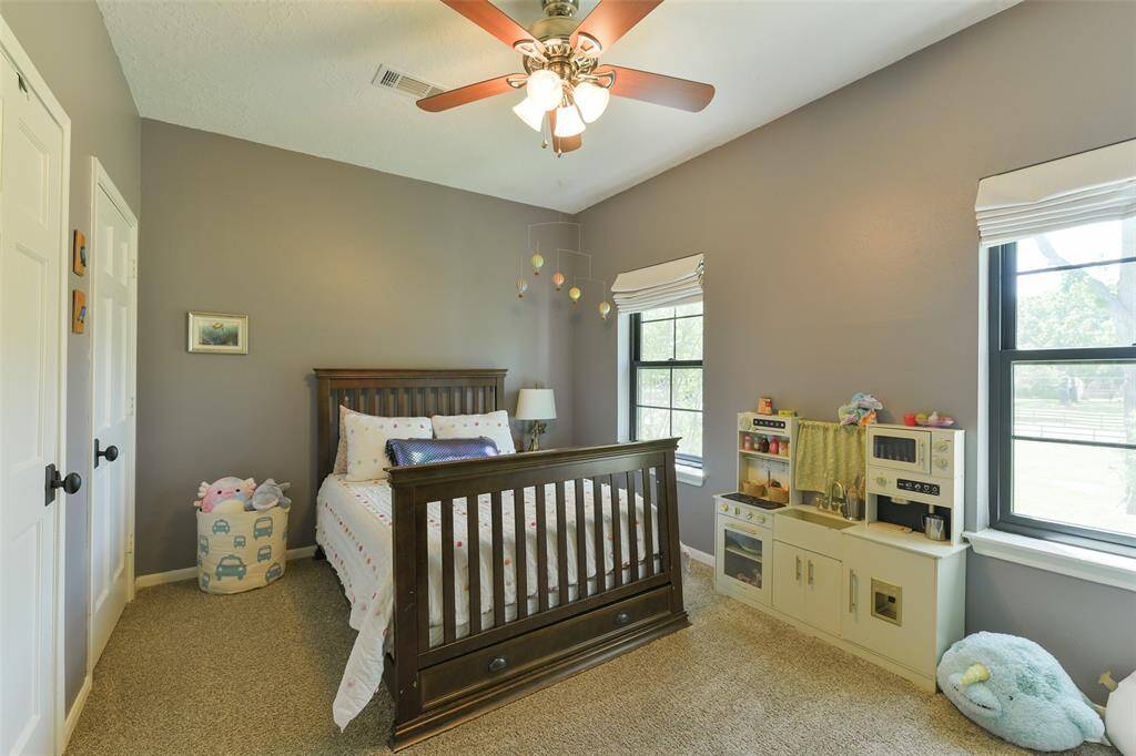 2nd bedroom upstairs with walk in closet, Roman shades and ceiling fan.