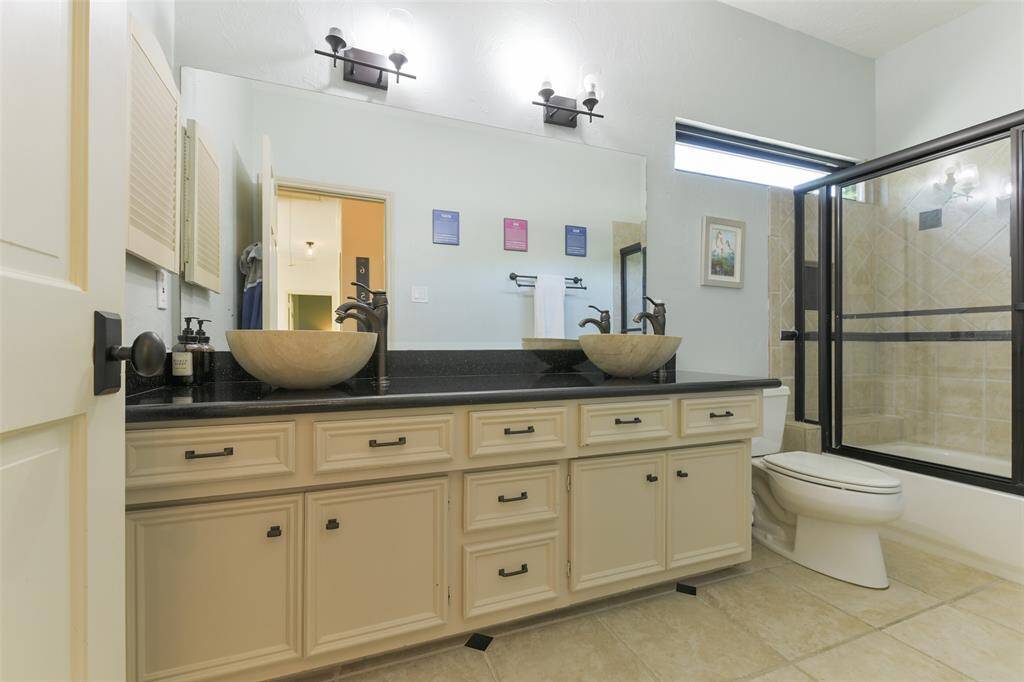 Newly remodeled 2nd bathroom upstairs with dual vessel sinks, new light fixtures and shower/tub combo with sliding glass door.