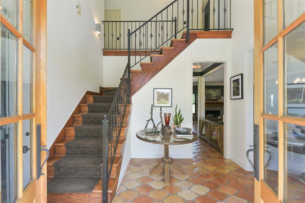 Formal Entryway with office on the left and open concept dining room on the right--note the gorgeous use of new Saltillo tile throughout the downstairs coupled with hardwood stairs and wrought iron.