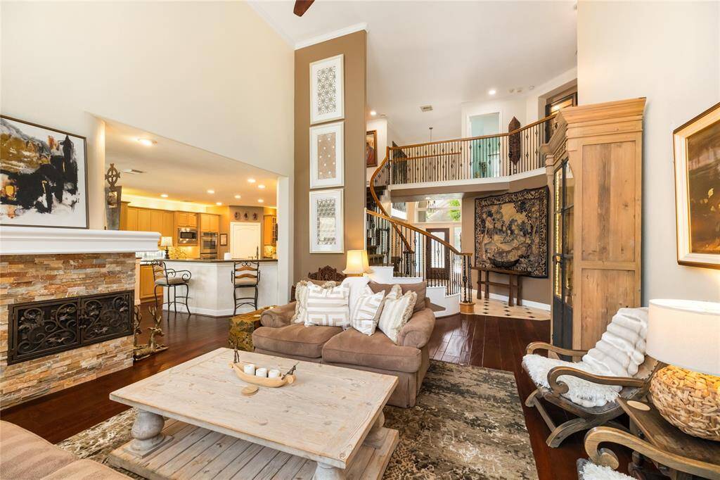 A space that radiates warmth and elegance. From the graceful spiral staircase to the inviting stone fireplace, this living room exudes luxury and comfort. Soaring ceilings and an open flow into the kitchen enhance the airy, spacious feel. Warm tones, plush seating, and tasteful art pieces elevate the atmosphere, making this the perfect place to unwind or entertain.