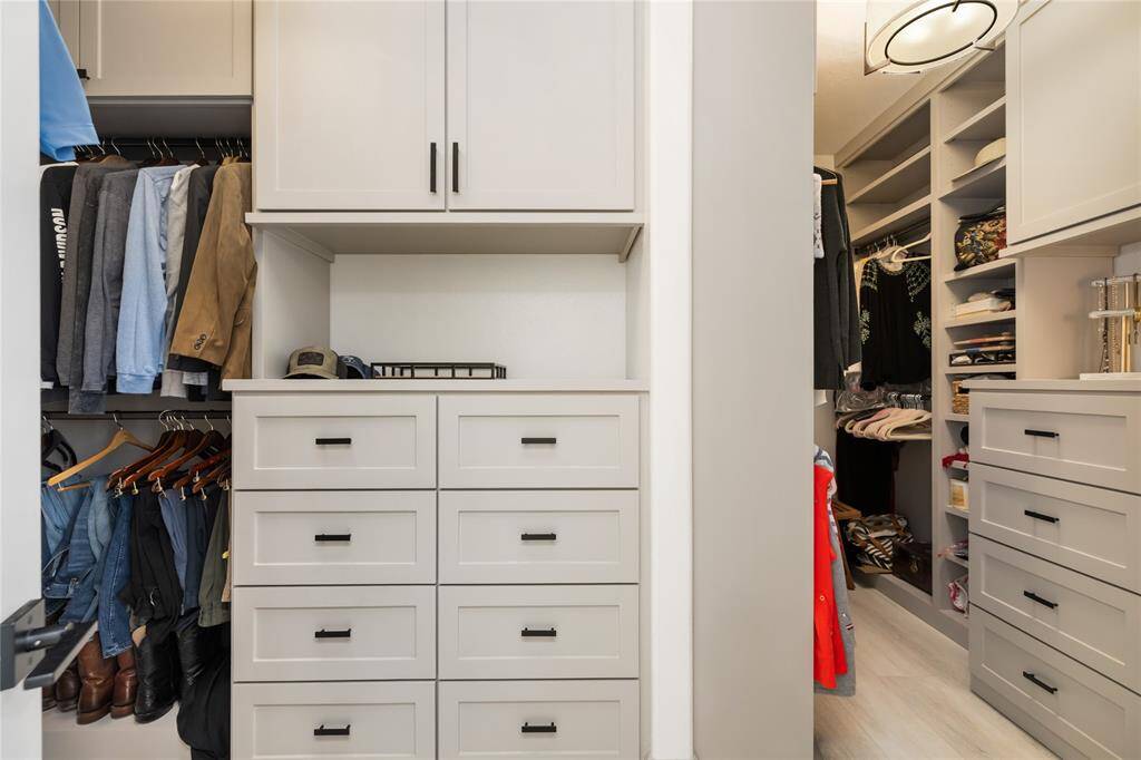 Effortless organization meets refined design. This expansive walk-in closet offers generous storage with custom shelving, ample hanging space, and multiple built-in drawers. A sleek, neutral palette enhances the streamlined layout, creating a space that’s as functional as it is beautifully designed.