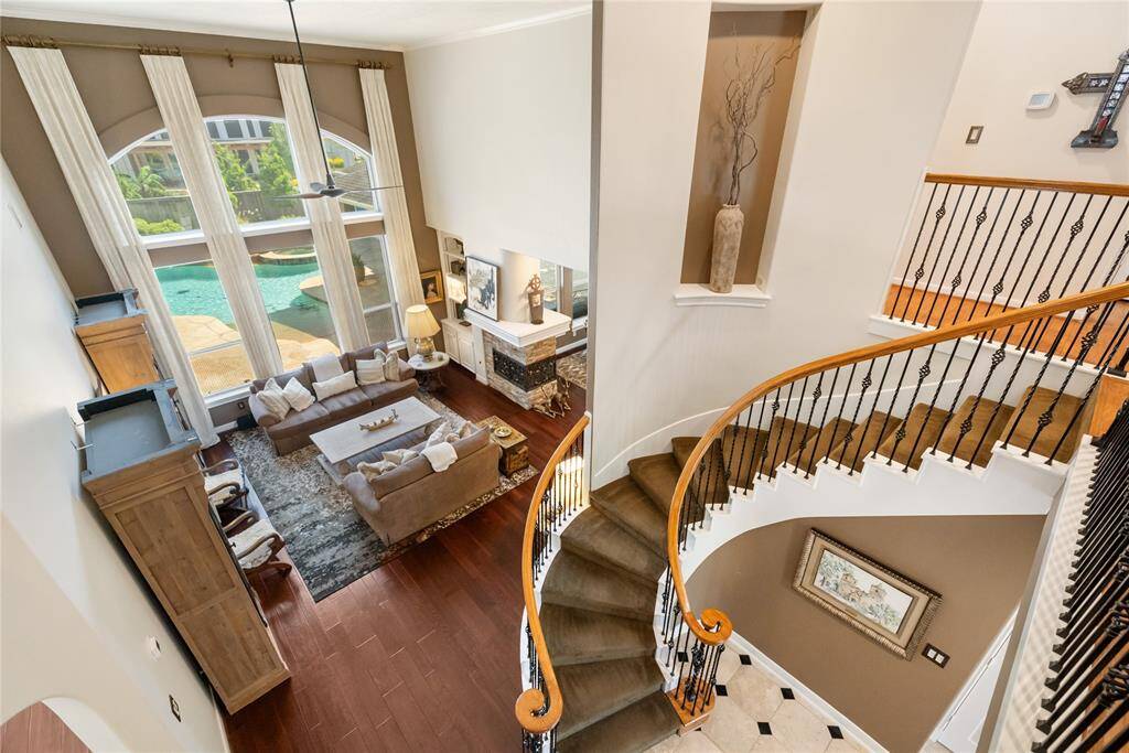 Imagine hosting friends, relaxing with family, or simply enjoying the view of the backyard pool through expansive windows. With soaring ceilings, a stunning spiral staircase, and rich hardwood floors, this open living space invites you to envision it as the perfect setting for both elegant gatherings and cozy everyday moments.