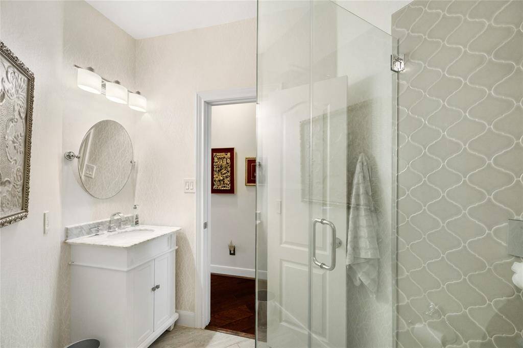 This thoughtfully designed bathroom features a sleek glass-enclosed shower, marble-topped vanity, and eye-catching tile work. Contemporary lighting and a soft, neutral palette complete the space, creating a fresh and inviting atmosphere with timeless appeal.