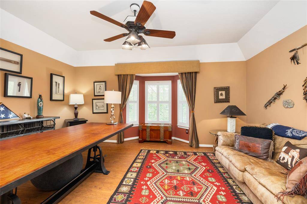 A flexible space to suit your lifestyle. This inviting room, with its warm earth tones and natural light from a bay window, offers endless possibilities. Whether used as a formal living area, home office, or media room, the layout easily adapts to your needs. A ceiling fan adds comfort, while the neutral decor and thoughtful design create a space that is both relaxing and functional.